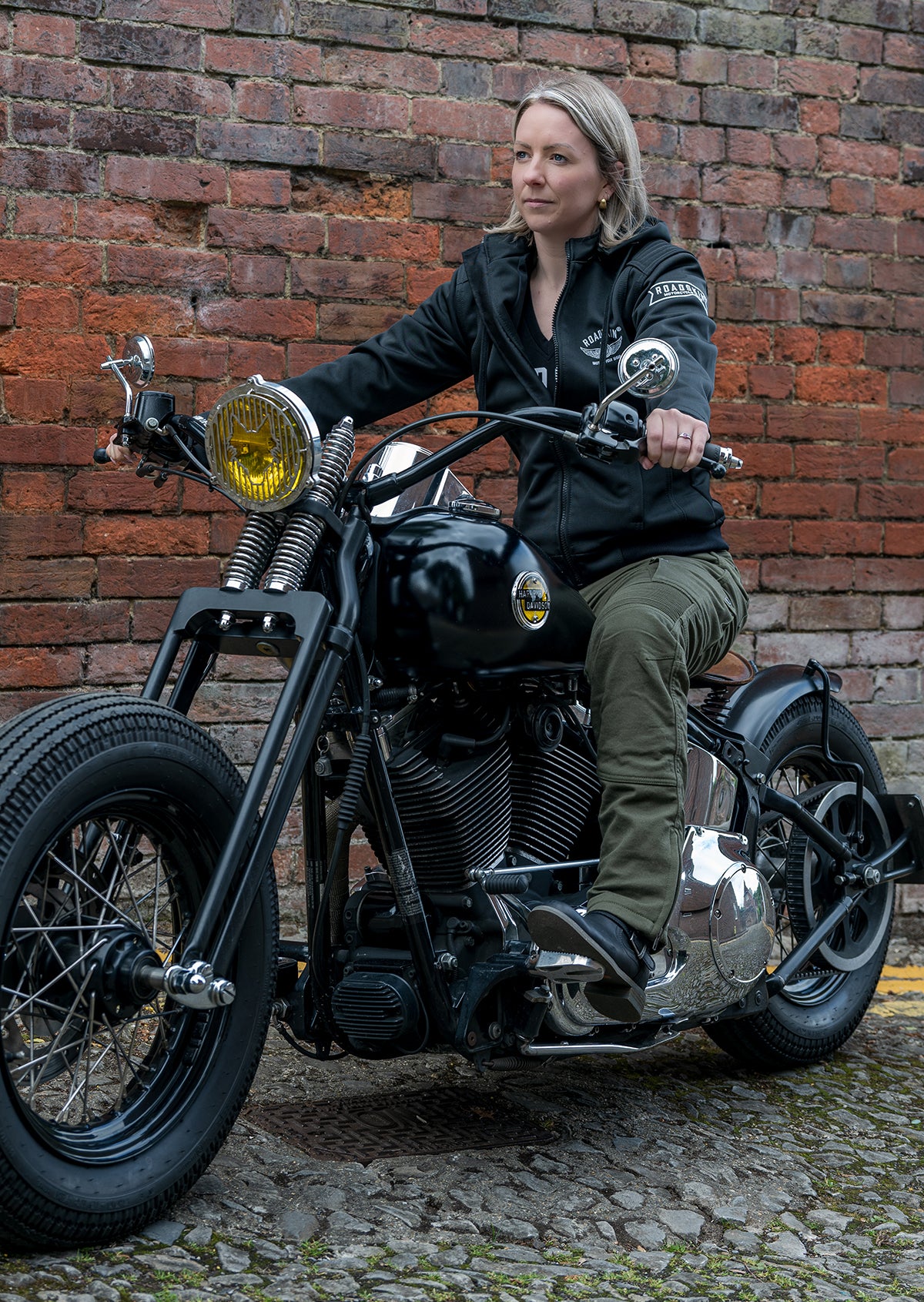 Lady on a motorcycle wearing olive coloured motorcycle trousers.