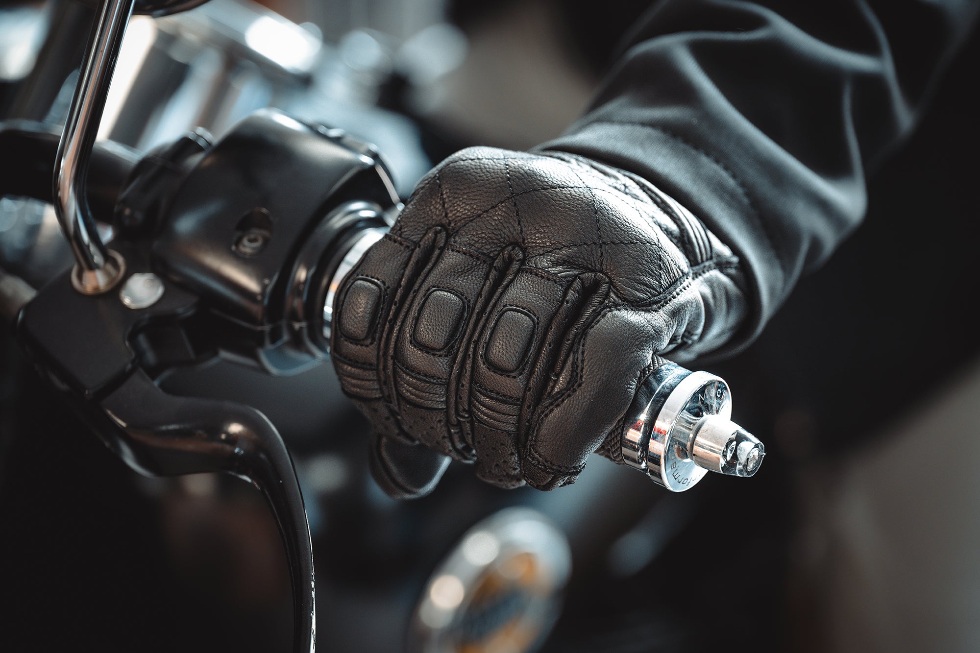 Close-up of a gloved hand gripping motorcycle handlebars