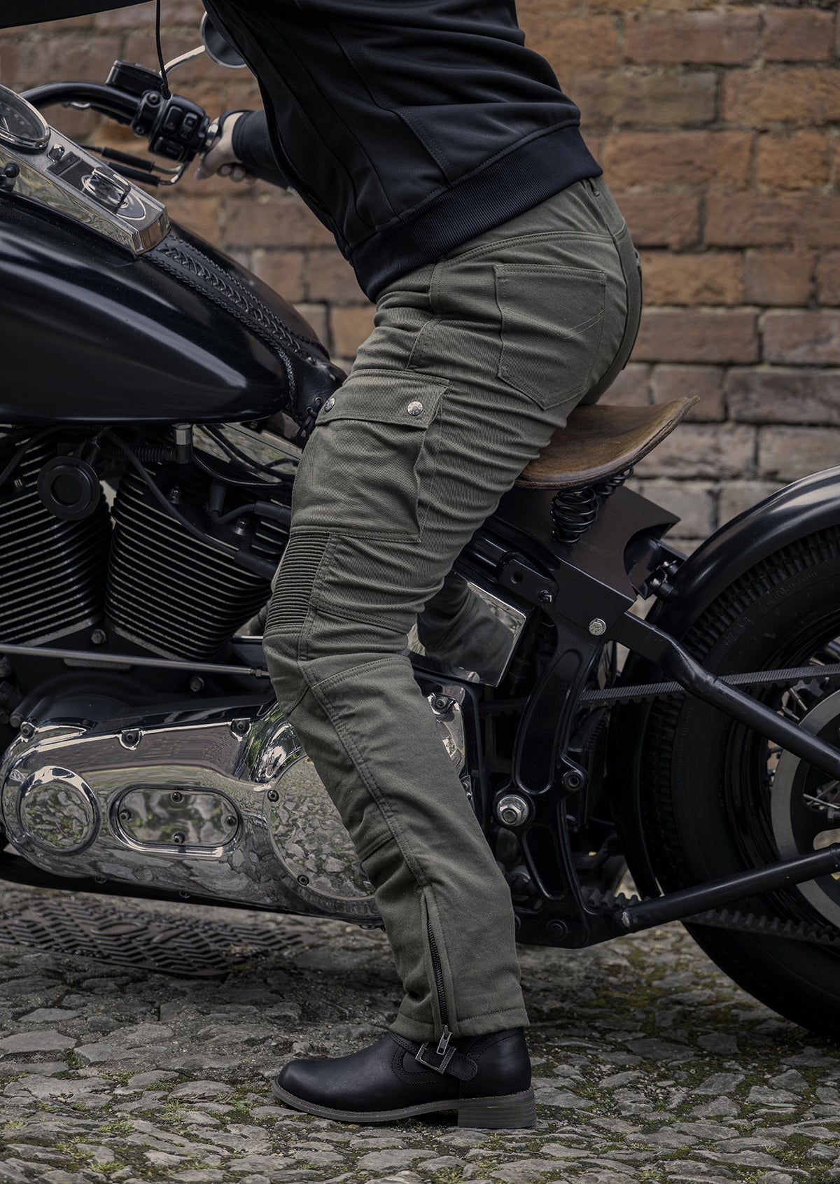 Lady sitting on motorcycle wearing olive coloured motorcycle trousers, side view.