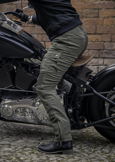 Lady sitting on motorcycle wearing olive coloured motorcycle trousers, side view.