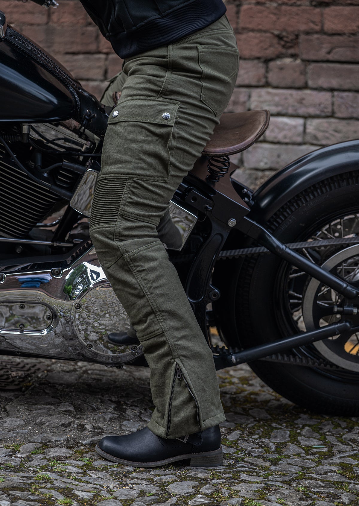 Lady sitting on motorcycle wearing olive coloured motorcycle trousers, side view.